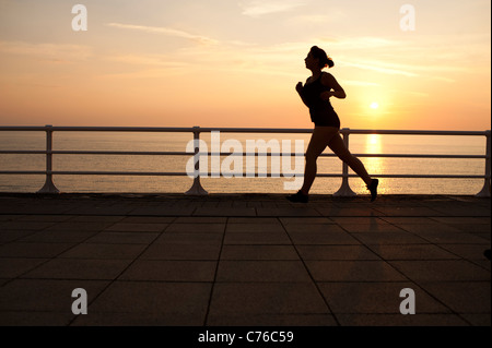 Silhouette d'une femme jogger running jogging au crépuscule sur la promenade d'Aberystwyth au Pays de Galles, Royaume-Uni 1 septembre 2011 Banque D'Images