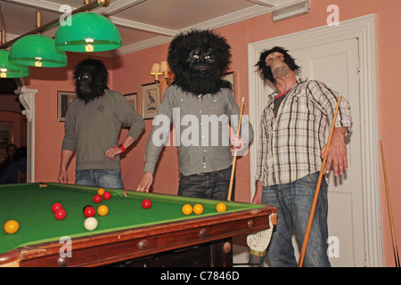 Les hommes portant des masques de singe jouant au billard Banque D'Images