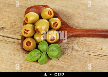 Olives dans une cuillère en bois d'une feuille de basilic sur old Weathered Wood Banque D'Images