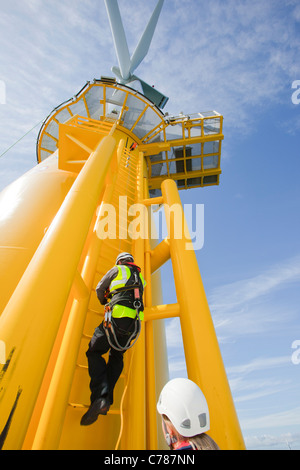 Un travailleur l'ascension d'une éolienne à l'éolien offshore Walney. Banque D'Images