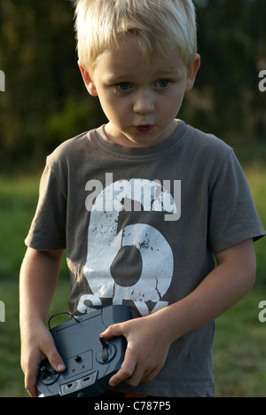 Portrait de jeune enfant garçon blond aux commandes d'un modèle d'avion télécommandé Banque D'Images