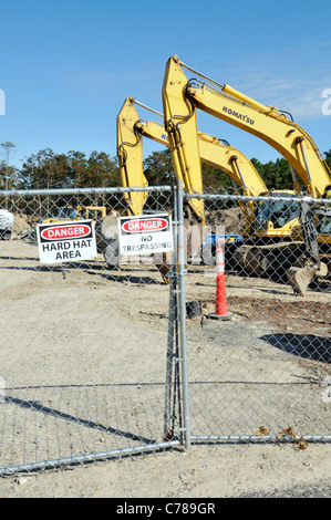 Site de construction d'équipement lourd entouré de clôture métallique avec attention, danger et casque de signes. USA Banque D'Images