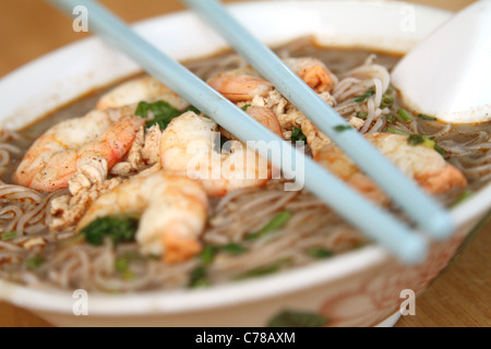 Un bol de Laksa malais, une base de noix de coco, soupe de curry est assis avec des baguettes et cuillère. Banque D'Images