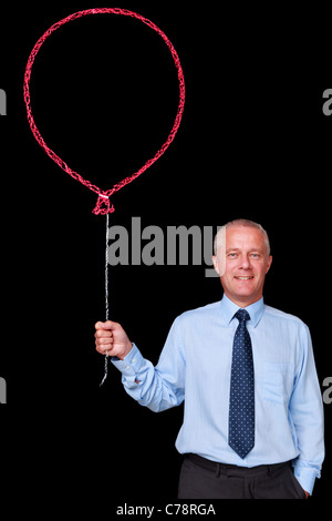 Photo d'un homme d'âge mûr sur un fond noir tenant un grand ballon dessiné à la craie rouge Banque D'Images