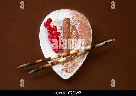 Une praline au chocolat sur une plaque blanche avec la poudre de cacao et de groseille rouge Banque D'Images