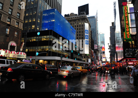 Tarmac humide réflexions néon vue, vers Times Square, du trafic et des personnes, la 7e Avenue, près de l'Applebee's, New York City Banque D'Images