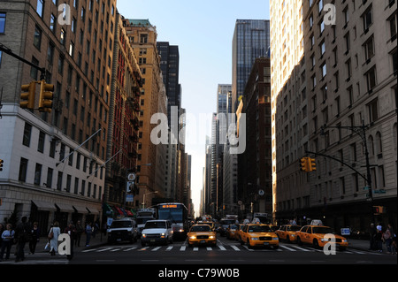 Voir tôt le matin, de Central Park South, voitures taxis jaunes passage piétons 6ème Avenue 'gratte-ciel' alley, New York City Banque D'Images