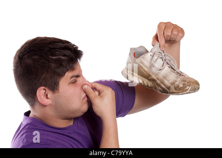 Un adolescent ses narines pincées fermé plus de l'odeur dégagée de la chaussure de sport qu'il occupe. Banque D'Images