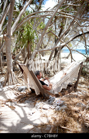 Guest dans le hamac sur la plage sous les arbres Pandanus Wilson Island Resort l'Île Wilson partie de la Capricornia Cays Nat Banque D'Images