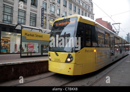 Un déménagement (floue) Manchester Metrolink tram à l'arrêt de la rue du marché dans le centre-ville. Banque D'Images