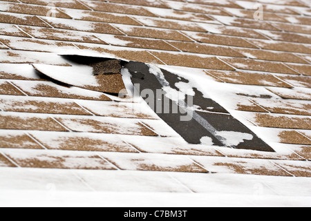 Les bardeaux de toit endommagé une maison emportée par le vent d'une tempête d'hiver avec de forts vents. Banque D'Images