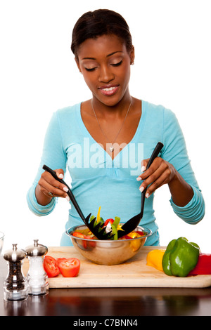 Belle jeune femme consciente de la santé sain salade tossing organiques en cuisine, isolé. Banque D'Images