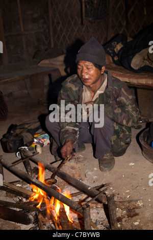 L'Inde, Nagaland, Naga Konyak Longwa, homme assis sur l'opium de fusion feu ronde spoon Banque D'Images