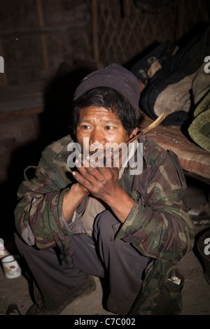 L'Inde, Nagaland, Naga Konyak Longwa, respiration de l'homme dans le résidu d'opium fondu sur spoon Banque D'Images