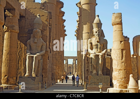 Assis colosses de Ramsès II et de la colonnade d'Amenhotep III, le temple de Louxor, Louxor, Egypte Banque D'Images