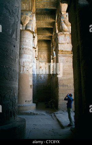 Un touriste prend une photo dans la grande salle hypostyle du Temple d'Hathor à Dendérah, Egypte Banque D'Images