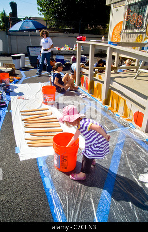 Un jeune bénévole des femmes et ses filles peinture décorations sur un bâtiment de ville au cours d'un programme d'embellissement de la collectivité. Banque D'Images