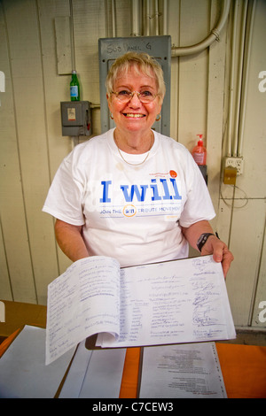 A smiling woman volunteer montre une liste d'autres bénévoles à un organisme de bienfaisance distribution gratuite de nourriture. Banque D'Images