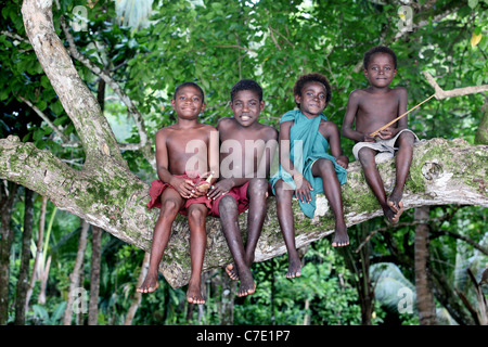 Les garçons de l'emplacement sur un tronc d'un arbre, l'île de Bougainville, en Papouasie-Nouvelle-Guinée Banque D'Images