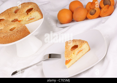 Une tranche de Tarte aux abricots servi sur une plaque blanche. Tarte aux abricots sur un cake stand et abricots du flou en arrière-plan Banque D'Images