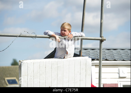 L'expulsion de Dale Farm. Un jeune garçon voyageur ressemble de derrière les barricades autour du site illégal pour éloigner les huissiers. Banque D'Images