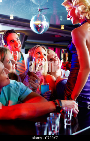 Photo de jolies filles et garçons à la recherche à l'un de leurs amis assis sur le bar Banque D'Images