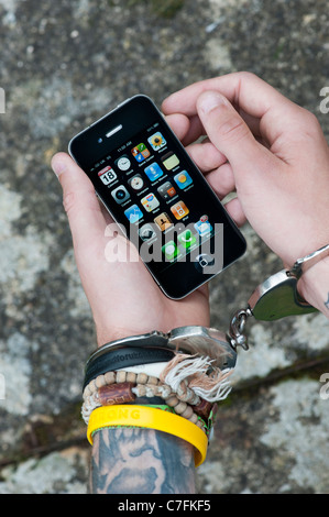 Adolescent menotté holding an Apple iphone. Banque D'Images