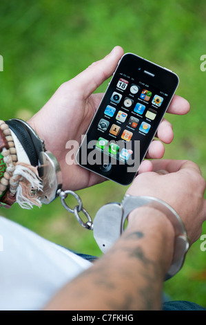 Adolescent menotté holding an Apple iphone. Banque D'Images