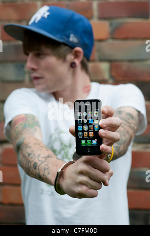 Adolescent menotté holding an Apple iphone. Banque D'Images