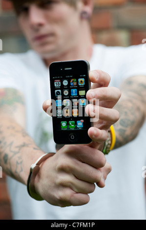 Adolescent menotté holding an Apple iphone. Banque D'Images