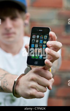 Adolescent menotté holding an Apple iphone. Banque D'Images