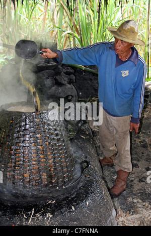 L'homme verse de Sumatra, jus de canne à sucre dans l'électrique au cours du processus de raffinage du sucre Village Banque D'Images