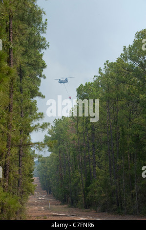 Hélicoptère transporte l'eau vers l'incendie dans la forêt de pins près de Bastrop, Texas, 30 milles à l'est d'Austin. Banque D'Images