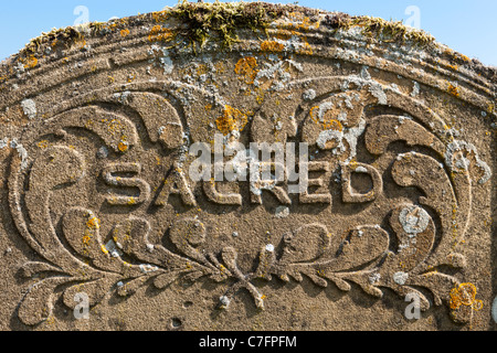 Sacré - sur une tombe dans un cimetière en pierre de Cotswold Banque D'Images