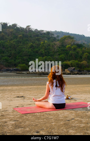 Une jeune femme faisant un yoga méditation poser sur une plage dans la lumière du matin Banque D'Images