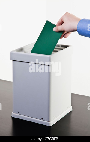 Un homme de mettre un bulletin vert dans une boîte de scrutin, close-up hands Banque D'Images