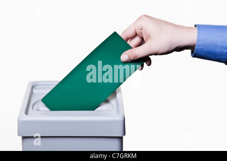 Un homme de mettre un bulletin vert dans une boîte de scrutin, close-up hands Banque D'Images