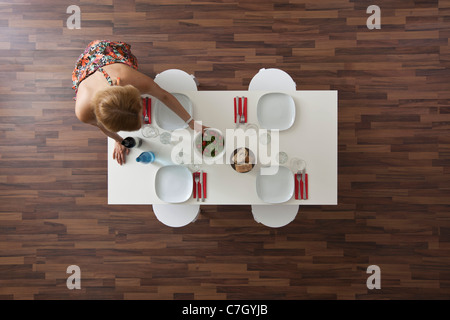 Réglage femme table de salle à manger pour dîner, overhead view Banque D'Images