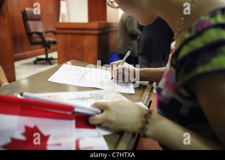 Jeune femme d'accepter la signature de documents de citoyenneté canadienne à une cérémonie de citoyenneté à Kitchener (Ontario) Banque D'Images