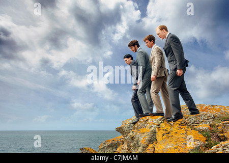 Hommes d'peering over cliff edge Banque D'Images