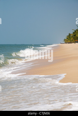 Mer d'Arabie se brisant sur la plage escarpée de Marari Beach, Mararikulam, près de Cochin Kerala Note bateaux de pêche Banque D'Images