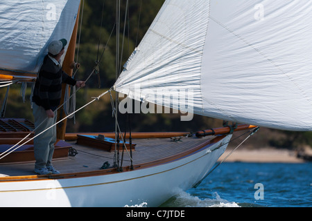 Un membre de l'équipe se penche sur l'enjoliveur de la GIB à bord du yacht conçu William Fife Clio Banque D'Images