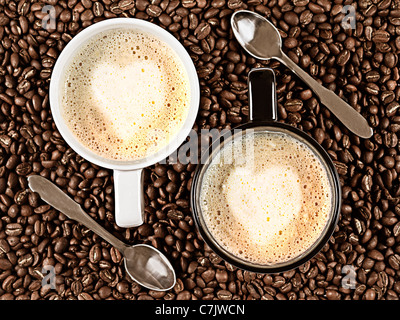 Deux tasses avec Cafee servent une grande variété de Latte avec Rosetta en forme de coeur entouré de grains de café et les cuillères Banque D'Images
