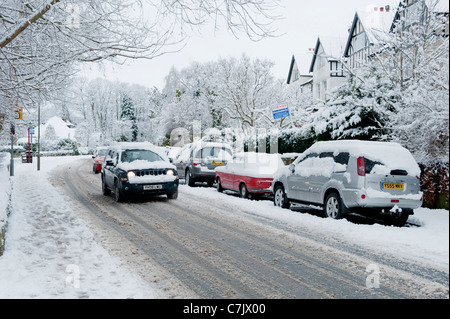 Rue du village d'hiver (conditions de conduite enneigées, voyage en jeep, voitures garées sur route, chaussée enneigée) - Burley à Wharfedale, Angleterre, GB, Royaume-Uni. Banque D'Images