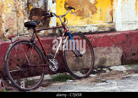 Vieux vélo rouillé stationné à une paroi colorée sur l'une des routes de la Galle, Sri Lanka Banque D'Images