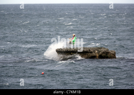 Un mannequin habillé comme un pêcheur se trouve sur un éperon rocheux dans la mer d'Irlande près du village de Waterfoot, sur le Comté d'Antrim Banque D'Images