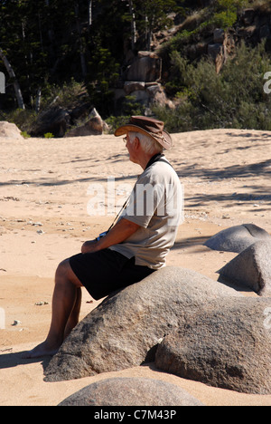 Homme assis sur la roche de granit sur la plage, Arthur bay, Magnetic island, Townsville, Queensland, Australie Banque D'Images