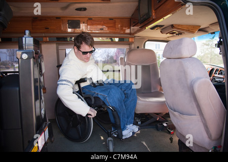 L'homme avec la moelle épinière d'entrer dans le siège du conducteur, de son fauteuil roulant en fourgonnette accessible Banque D'Images