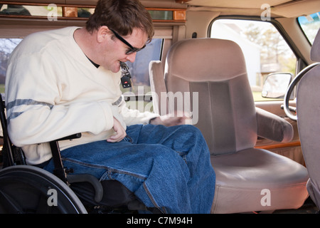 L'homme avec la moelle épinière d'entrer dans le siège du conducteur, de son fauteuil roulant en fourgonnette accessible Banque D'Images