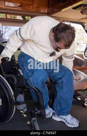 L'homme avec la moelle épinière d'entrer dans le siège du conducteur, de son fauteuil roulant en fourgonnette accessible Banque D'Images